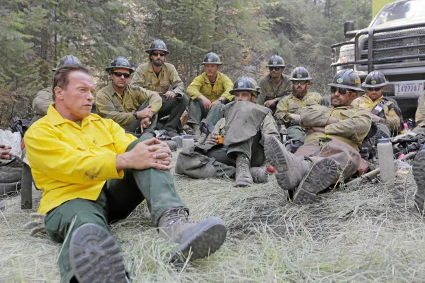 Arnold Schwarzenegger resting with firefighters between deployments