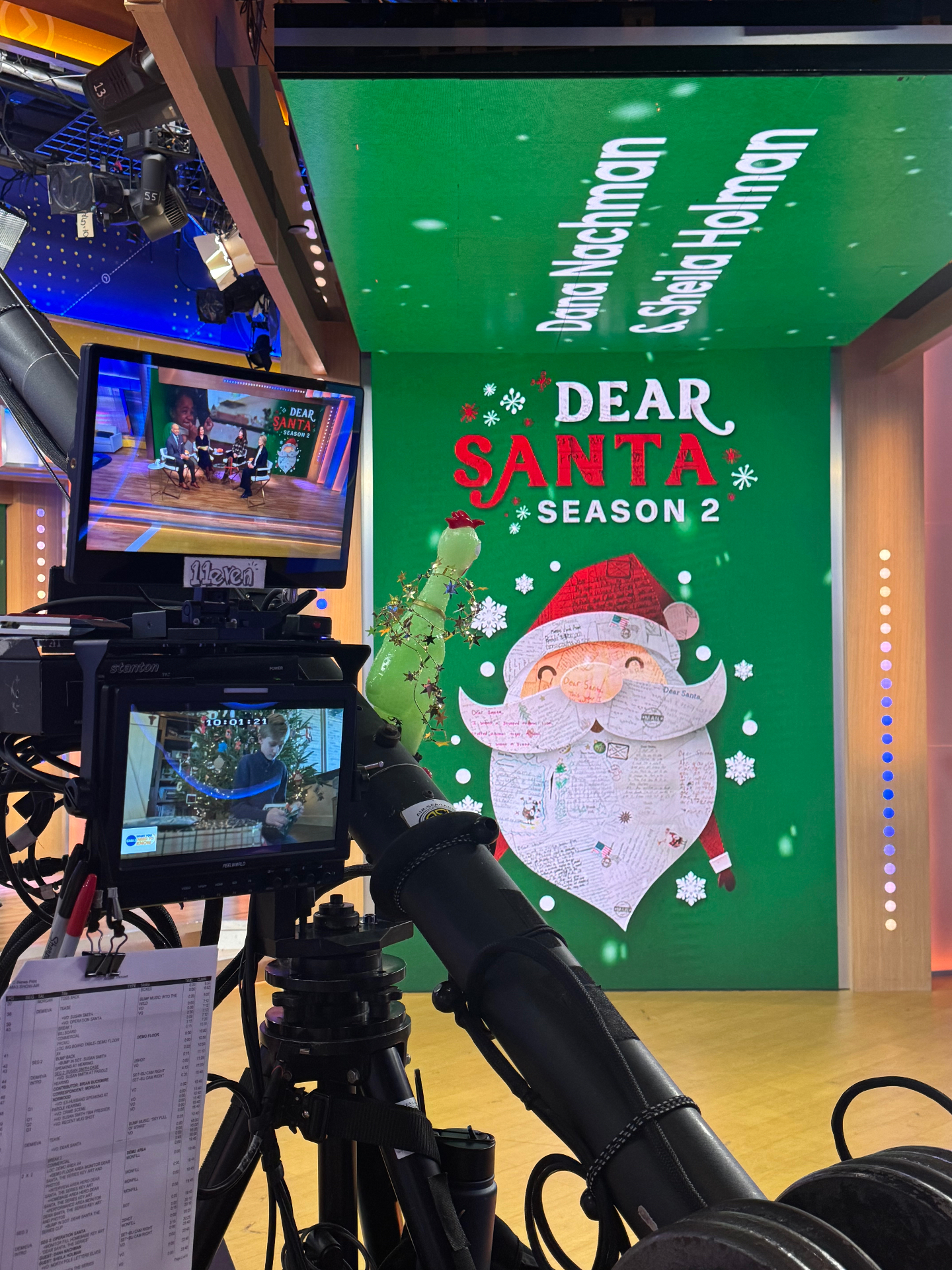 Broadcast camera and monitor foreground a Dear Santa Season 2 segment inside the studio.