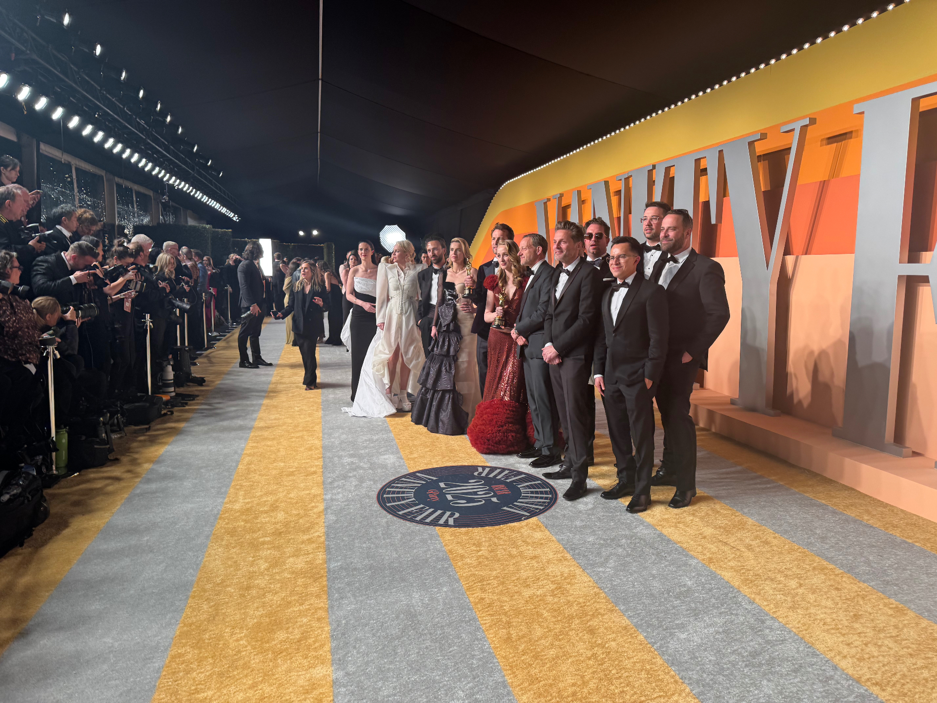 Filmmaking team posing on the Vanity Fair Oscar Party carpet with statuettes